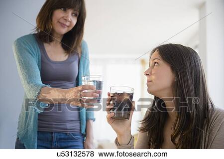 Mom encouraging teenage girl (14-15) to drink mineral water View Large Photo Image Stock Photo - Mom encouraging teenage girl (14-15) to drink mineral water. Fotosearch