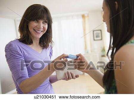 Stock Image - Mom giving teenage girl (14-15) credit card. Fotosearch