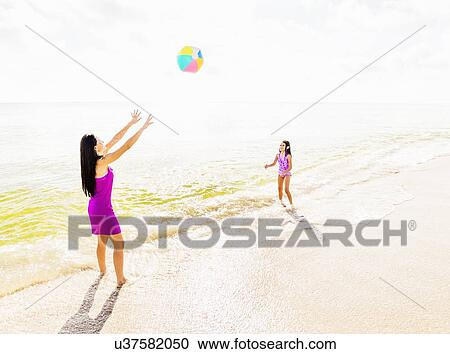 Mom throwing beach ball to her daughter (6-7) on beach View Large Photo Image Stock Image - Mom throwing beach ball to her daughter (6-7) on beach. Fotosearch