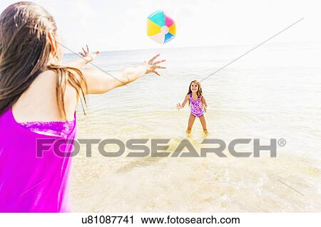 Mom throwing beach ball to her daughter (6-7) on beach View Large Photo Image Stock Image - Mom throwing beach ball to her daughter (6-7) on beach. Fotosearch