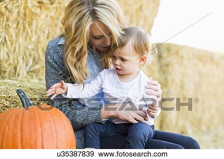 Mother and daughter (12-17 months) looking at large pumpkin View Large Photo Image Stock Photo - Mother and daughter (12-17 months) looking at large pumpkin. Fotosearch