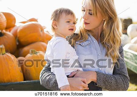 Mother and daughter (12-17 months) with pumpkins in background View Large Photo Image Stock Photograph - Mother and daughter (12-17 months) with pumpkins in background. Fotosearch