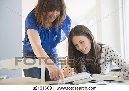 Stock Image - Mother helping daughter (14-15) with homework. Fotosearch