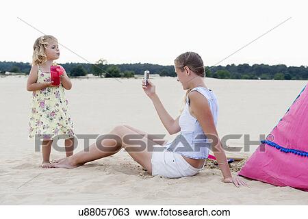 Mother taking picture of daughter (2-3) on beach View Large Photo Image Stock Image - Mother taking picture of daughter (2-3) on beach. Fotosearch