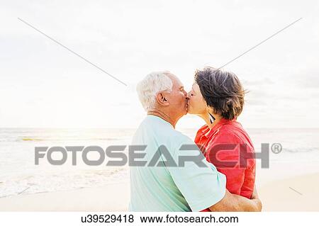 Older couple kissing on beach at sunrise View Large Photo Image Stock Photo - Older couple kissing on beach at sunrise. Fotosearch