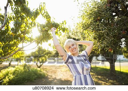 Picture - Portrait of blond woman in orchard. Fotosearch