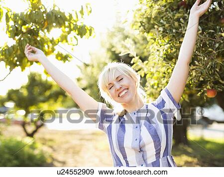 Stock Photo - Portrait of blond woman in orchard. Fotosearch
