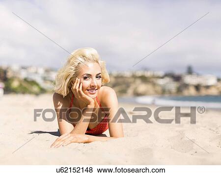 Stock Photo - Portrait of blond woman lying on beach. Fotosearch