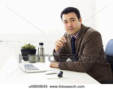 Stock Photography - Portrait of businessman sitting in office. Fotosearch