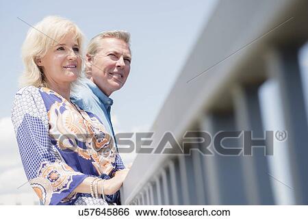 Stock Photograph - Portrait of couple leaning at railing, looking at view. Fotosearch