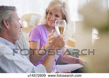 Portrait of couple sitting on sofa drinking white wine View Large Photo Image Stock Photo - Portrait of couple sitting on sofa drinking white wine. Fotosearch