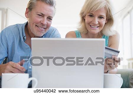 Portrait of couple using laptop, with credit card in view View Large Photo Image Stock Image - Portrait of couple using laptop, with credit card in view. Fotosearch