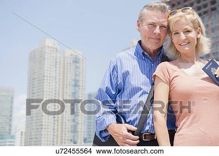Picture - Portrait of couple with passport against skyscrapers. Fotosearch