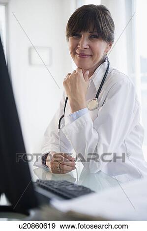 Portrait of doctor sitting at desk View Large Photo Image Stock Photo - Portrait of doctor sitting at desk. Fotosearch