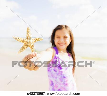 Portrait of girl (6-7) holding starfish on beach View Large Photo Image Stock Photo - Portrait of girl (6-7) holding starfish on beach. Fotosearch