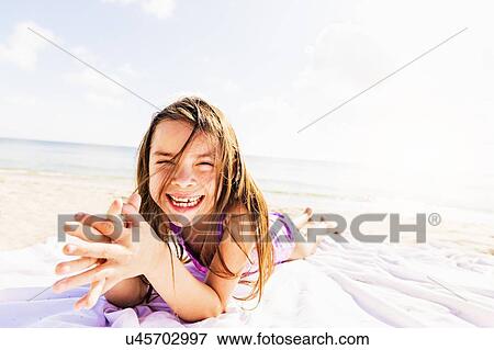 Stock Photo - Portrait of happy girl (6-7) sunbathing. Fotosearch