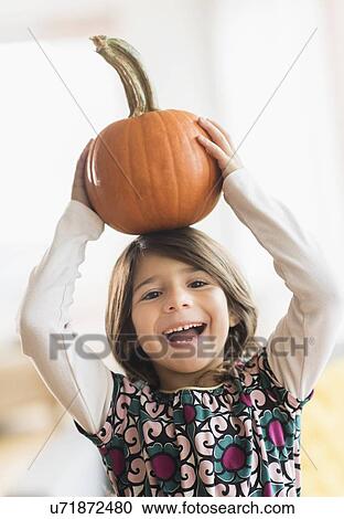 Portrait of happy girl (6-7) with pumpkin on head View Large Photo Image Stock Image - Portrait of happy girl (6-7) with pumpkin on head. Fotosearch