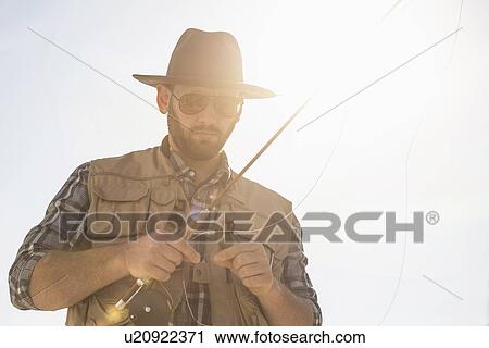 Stock Image - Portrait of man holding fishing rod. Fotosearch