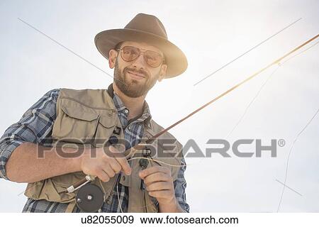 Stock Photo - Portrait of man holding fishing rod. Fotosearch