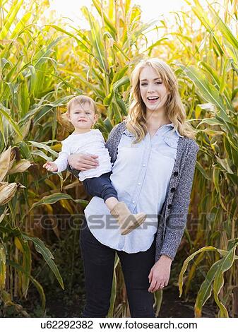 Stock Image - Portrait of mother and daughter (12-17 months) in corn field. Fotosearch