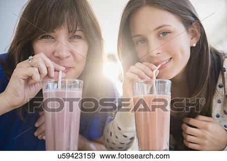Stock Photo - Portrait of mother and daughter (14-15) drinking milkshakes. Fotosearch