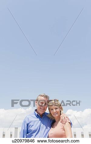 Portrait of smiling couple against sky View Large Photo Image Stock Photograph - Portrait of smiling couple against sky. Fotosearch