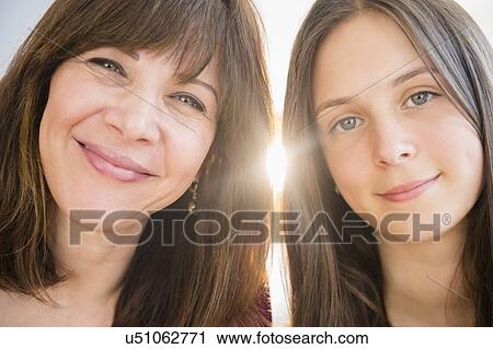 Stock Image - Portrait of smiling mom and daughter (14-15) indoors. Fotosearch