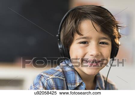 Stock Photography - Portrait of smiling schoolboy (6-7) in headphones . Fotosearch