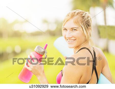 Stock Photo - Portrait of smiling woman drinking water. Fotosearch
