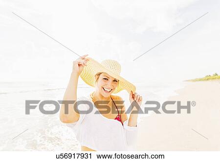 Portrait of smiling young woman on beach wearing sun hat View Large Photo Image Stock Image - Portrait of smiling young woman on beach wearing sun hat . Fotosearch