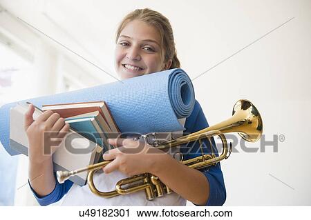 Portrait of teenage girl (12-13) holding rolled-up exercise mat, books, and trumpet View Large Photo Image Stock Image - Portrait of teenage girl (12-13) holding rolled-up exercise mat, books, and trumpet. Fotosearch