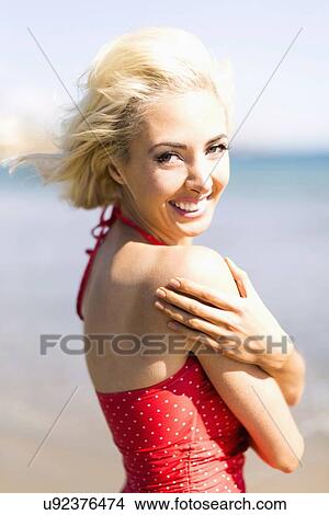 Picture - Portrait of woman wearing red swimming costume on beach. Fotosearch