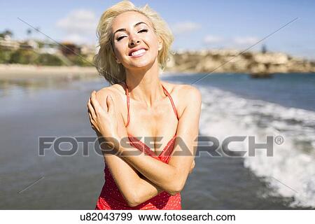Stock Photo - Portrait of woman wearing red swimming costume on beach. Fotosearch