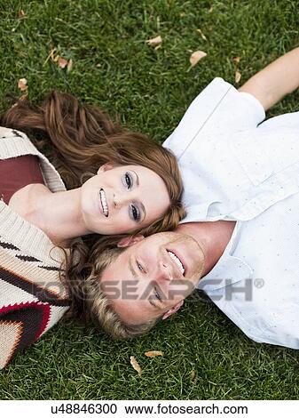 Portrait of young couple lying in grass View Large Photo Image Stock Image - Portrait of young couple lying in grass. Fotosearch