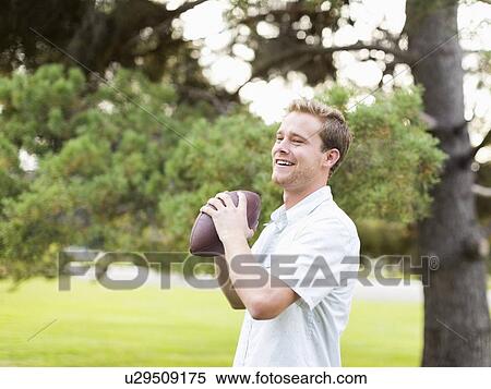 Stock Photography - Portrait of young man playing football in park. Fotosearch