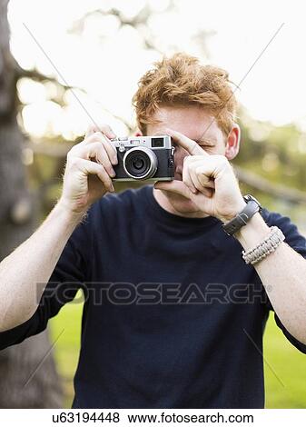 Stock Photo - Portrait of young man taking photos. Fotosearch