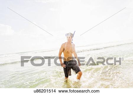 Portrait of young man walking in surf wearing scuba mask and snorkel View Large Photo Image Picture - Portrait of young man walking in surf wearing scuba mask and snorkel. Fotosearch