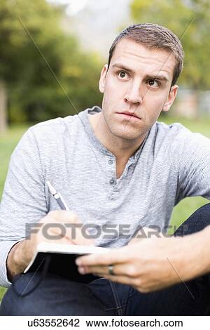 Stock Image - Portrait of young man writing journal. Fotosearch