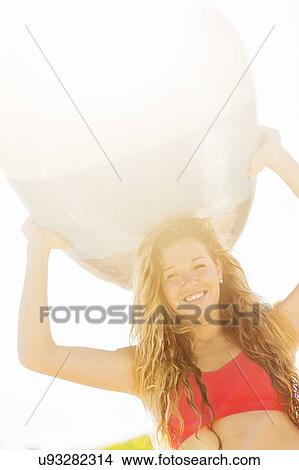 Portrait of young woman holding surfboard over head View Large Photo Image Picture - Portrait of young woman holding surfboard over head. Fotosearch