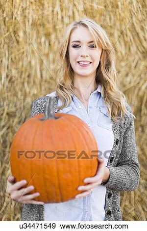 Portrait of young woman holding pumpkin View Large Photo Image Stock Photo - Portrait of young woman holding pumpkin. Fotosearch