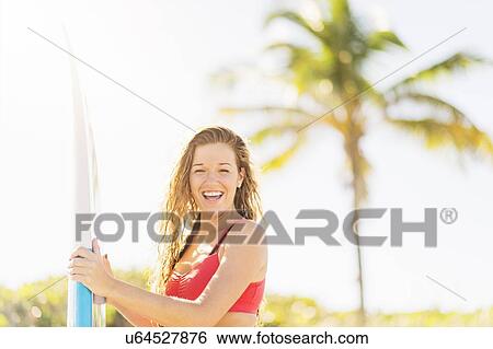 Portrait of young woman holding surfboard on beach View Large Photo Image Stock Photograph - Portrait of young woman holding surfboard on beach. Fotosearch