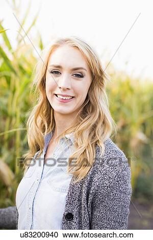 Stock Image - Portrait of young woman in corn field. Fotosearch