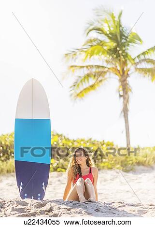 Portrait of young woman sitting near surfboard on beach View Large Photo Image Stock Photography - Portrait of young woman sitting near surfboard on beach. Fotosearch