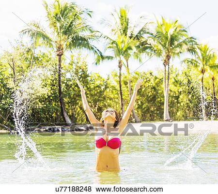 Portrait of young woman wearing bikini splashing water in tropical lagoon View Large Photo Image Stock Photo - Portrait of young woman wearing bikini splashing water in tropical lagoon. Fotosearch