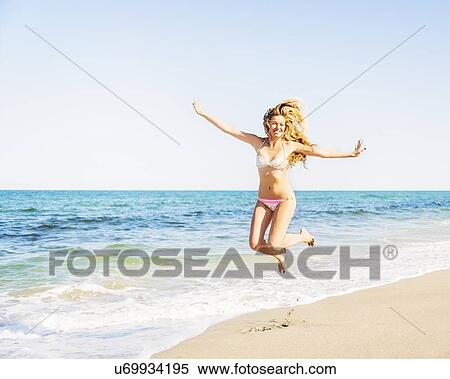 Portrait of young woman wearing bikini jumping on beach View Large Photo Image Stock Photography - Portrait of young woman wearing bikini jumping on beach. Fotosearch