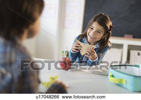 Stock Photograph - Pupils (6-7) eating lunch in classroom. Fotosearch