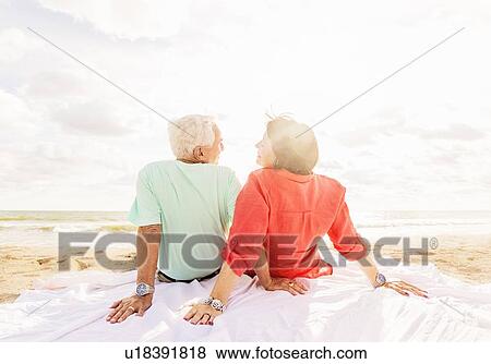 Rear view of couple looking at each other on beach at sunrise View Large Photo Image Stock Photo - Rear view of couple looking at each other on beach at sunrise. Fotosearch