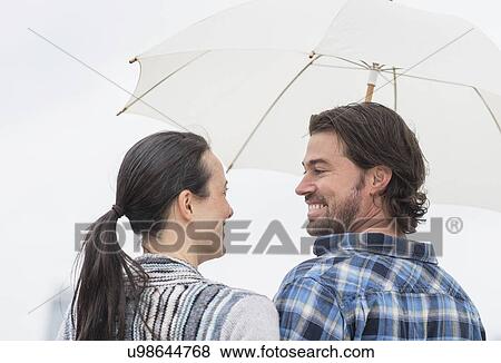 Rear view of couple under umbrella View Large Photo Image Stock Photo - Rear view of couple under umbrella. Fotosearch