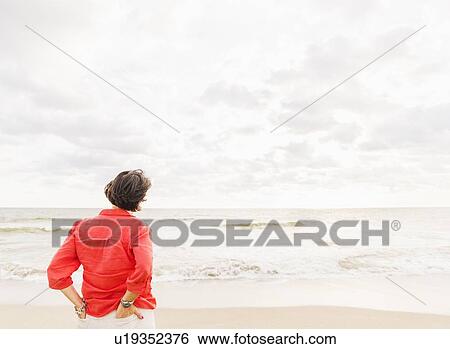 Stock Photograph - Rear view of woman looking at ocean. Fotosearch