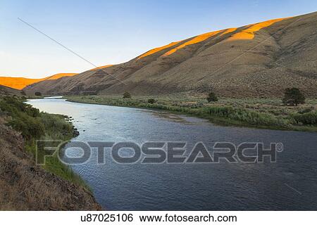 Stock Photograph - River at foot of hills. Fotosearch